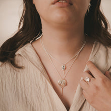 Load image into Gallery viewer, Female, Brunette, mini horseshoe crab earrings and necklace, large horseshoe crab necklace, ram’s horn ring, sandy, beige, neutral background