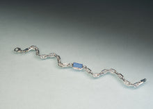Load image into Gallery viewer, A silver wavy chain bracelet featuring a central rectangular light blue stone, displayed on a neutral gray gradient background.