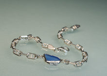 Load image into Gallery viewer, A silver-toned chain bracelet featuring a polished blue stone centerpiece, displayed on a light gray reflective surface.