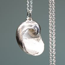 Load image into Gallery viewer, Silver shell pendant on a chain against a gray background