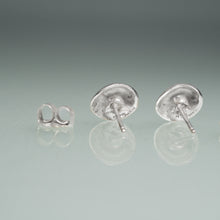 Load image into Gallery viewer, Pair of silver stud earrings on a reflective surface with a gray background