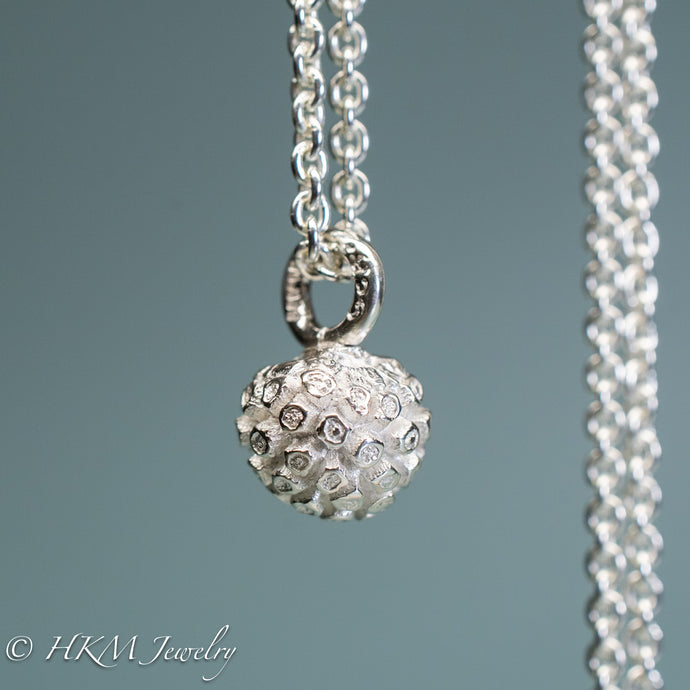 close up of cast silver kousa dogwood fruit necklace by hkm jewelry in polished finish