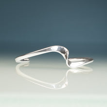 Load image into Gallery viewer, Silver bracelet on a reflective surface with a gradient background