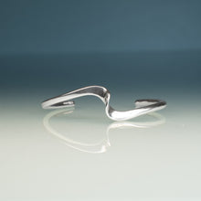 Load image into Gallery viewer, Silver bracelet on a reflective surface with a gradient background