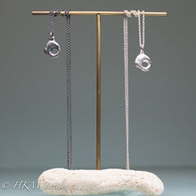 Load image into Gallery viewer, small hag stone necklaces cast in sterling silver by hkm jewelry on brass and coral jewelry display