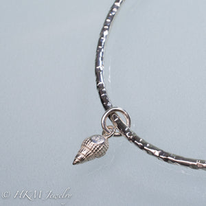 back of mud snail charm on hammered silver bangle by hkm jewelry
