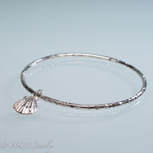 hammered silver bangle with lion's paw scallop shell charm by hkm jewelry