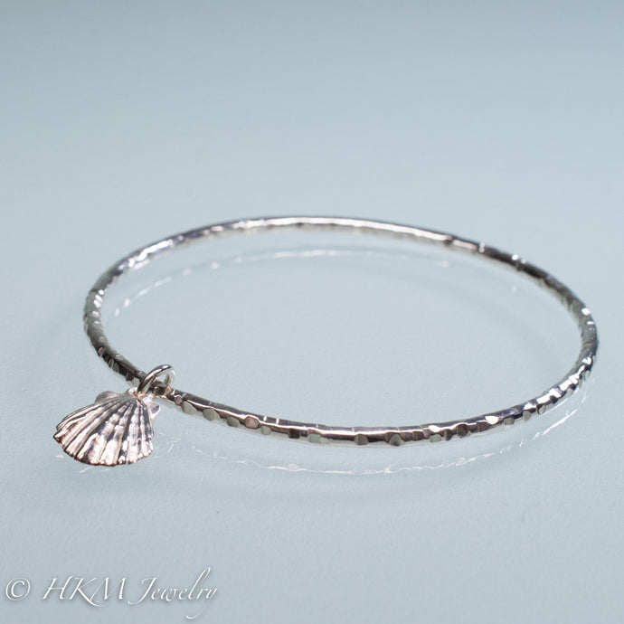hammered silver bangle with lion's paw scallop shell charm by hkm jewelry