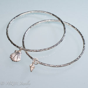 hammered silver bangles with mud snail and lion's paw shell charms by hkm jewelry