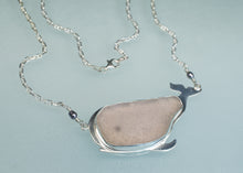 Load image into Gallery viewer, A whale-shaped pendant necklace featuring a smooth, polished sea glass insert in a silver-toned metal setting, suspended from a delicate silver chain against a light blue background.
