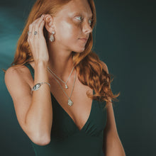 Load image into Gallery viewer, Woman wearing jewelry including earrings, a necklace, and a bracelet against a dark background