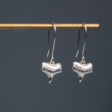 Load image into Gallery viewer, cast silver small shark tooth earrings on brass earring stand with blue gradient background