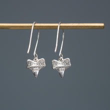 Load image into Gallery viewer, underside of cast silver small shark tooth earrings on brass earring stand with blue gradient background