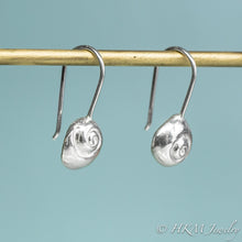 Load image into Gallery viewer, Silver spiral earrings hanging on a rod against a light blue background