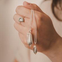 Load image into Gallery viewer, Hand holding a silver necklace with two pendant drops against a neutral background