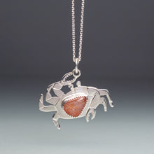 Load image into Gallery viewer, Silver crab pendant with a red stone on a chain against a gray background
