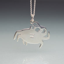 Load image into Gallery viewer, Silver crab-shaped pendant on a chain against a gray background