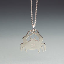 Load image into Gallery viewer, Silver crab pendant on a chain against a gray background