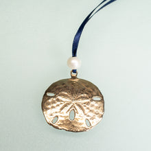 Load image into Gallery viewer, cast bronze sand dollar ornament from stone harbor nj with freshwater pearl and navy blue satin ribbon by hkm jewelry on seafoam background
