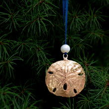 Load image into Gallery viewer, close up of cast bronze sand dollar ornament from stone harbor nj with freshwater pearl and navy blue satin ribbon by hkm jewelry on evergreen tree