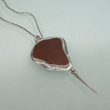 Load image into Gallery viewer, Necklace with a brown sea glass pendant on a light blue background