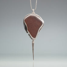 Load image into Gallery viewer, Silver pendant shaped like a horseshoe crab with a brown sea glass on a gray background