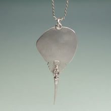 Load image into Gallery viewer, Silver pendant with a long, thin blade-like extension on a gradient background