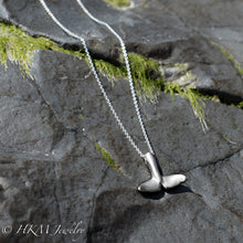 Load image into Gallery viewer, underside of whale tail necklace in sterling silver by hkm jewelry on a jetty rock with algae