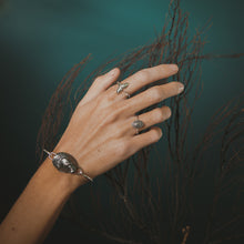 Load image into Gallery viewer, Hand wearing a silver bracelet and ring with a dark background