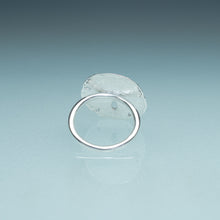 Load image into Gallery viewer, underside view of silver sand dollar ring on blue green gradient background