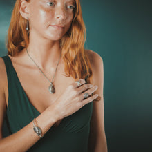 Load image into Gallery viewer, Woman wearing green dress with jewelry against a dark background
