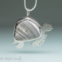 Load image into Gallery viewer, hand sawn and pierced sterling silver sea turtle necklace with fossilized clam shell shard bezel setting
