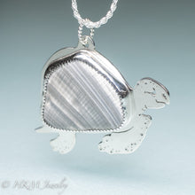 Load image into Gallery viewer, side view of hand sawn and pierced sterling silver sea turtle necklace with fossilized clam shell shard bezel setting
