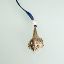Load image into Gallery viewer, cast bronze lightning whelk ornament from key west florida with freshwater pearl and navy blue satin ribbon by hkm jewelry on blue background