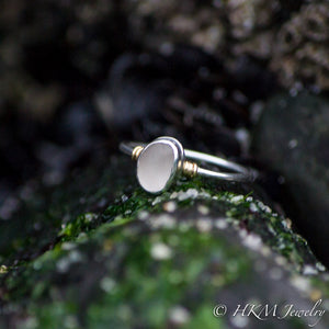 side view of a raw cape may diamond ring with 14k wrapped knot details over silver by hkm jewelry laying in green seaweed