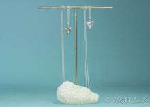 Load image into Gallery viewer, bull shark teeth necklaces cast in polished or oxidized silver by hkm jewelry on brass and coral jewelry stand