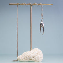 Load image into Gallery viewer, underside view of the cast fiddler crab claw necklace in recycled silver hanging from brass and coral necklace display on a blue background by hkm jewelry