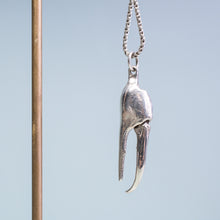 Load image into Gallery viewer, close up view of the cast fiddler crab claw necklace in recycled silver hanging from brass and coral necklace display on a blue background by hkm jewelry