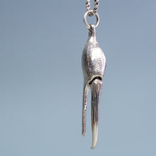 Load image into Gallery viewer, top view of the cast fiddler crab claw necklace in recycled silver hanging from brass and coral necklace display on a blue background by hkm jewelry