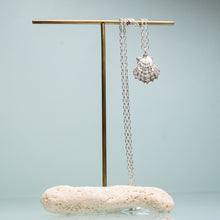 Load image into Gallery viewer, large lions paw scallop shell necklace in polished sterling silver on coral and brass jewelry stand by hkm jewelry