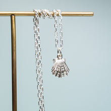 Load image into Gallery viewer, close up of small lions paw scallop shell necklace in polished sterling silver on coral and brass jewelry stand by hkm jewelry