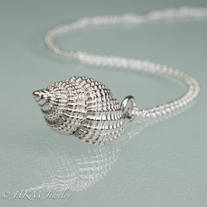 close up view of cast silver nutmeg shell necklace in a polished finish by hkm jewelry