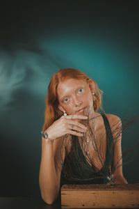 Female, red-head, lion’s paw pearl earrings, oyster seed cuff, sea tail ring, limpet ring, green/blue, teal, underwater background