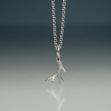 Load image into Gallery viewer, A silver branch-shaped pendant necklace with a textured, glittering finish, hanging from a silver ball chain against a dark gray gradient background with a soft reflection below.
