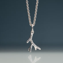 Load image into Gallery viewer, A sterling silver necklace with a textured branch-shaped pendant, suspended against a dark gray gradient background with a soft reflection below.
