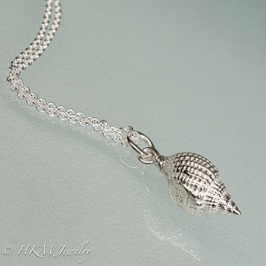 close up side view of cast silver nutmeg shell necklace in a polished finish by hkm jewelry