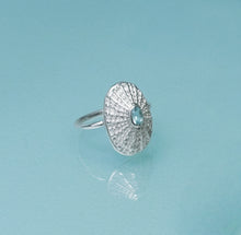 Load image into Gallery viewer, Silver ring with a blue gemstone on a light blue background
