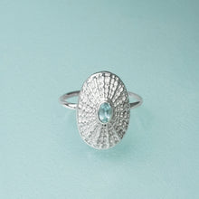 Load image into Gallery viewer, Silver seashell ring with a blue gemstone on a light blue background
