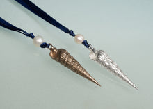 Load image into Gallery viewer, Two conical shell pendants on a blue cord with pearls against a light green background
