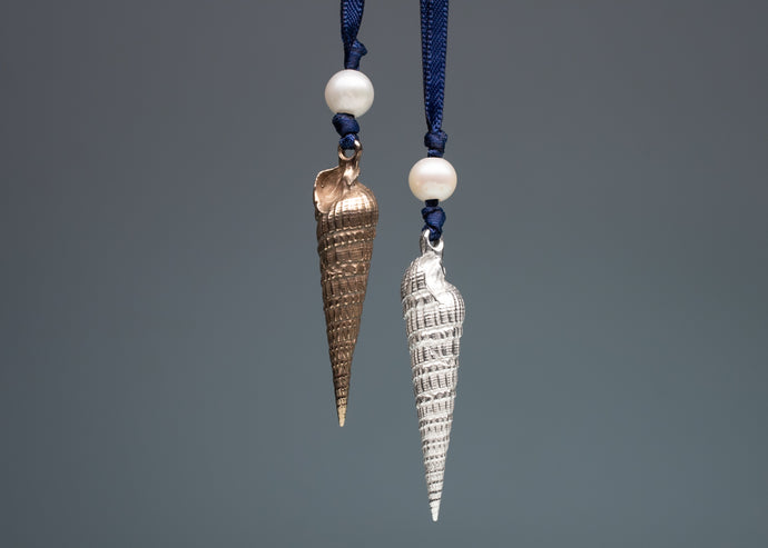 Two shell-shaped pendants on blue ribbons against a gray background